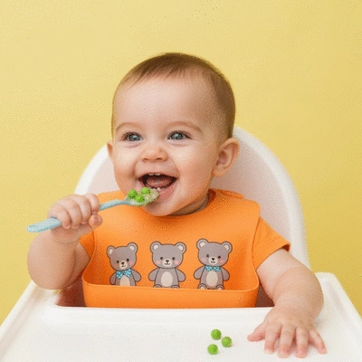 A baby happily eating a spoonful of pureed food, with a focus on healthy eating